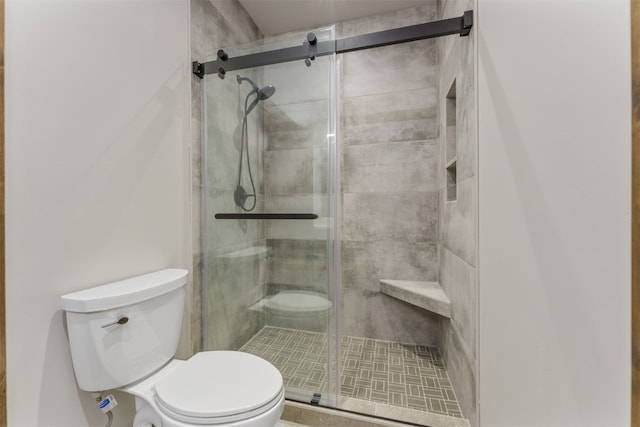 bathroom with a shower with shower door and toilet