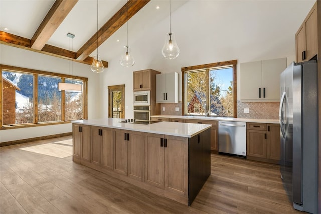 kitchen featuring a center island, backsplash, hanging light fixtures, light wood-type flooring, and appliances with stainless steel finishes