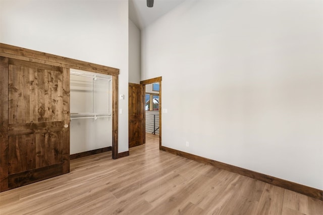 unfurnished bedroom with light hardwood / wood-style flooring, high vaulted ceiling, and a closet