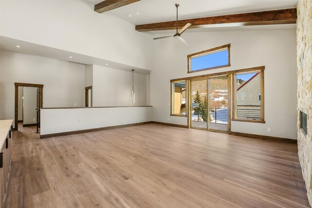 unfurnished living room featuring a fireplace, a high ceiling, light wood-type flooring, and ceiling fan