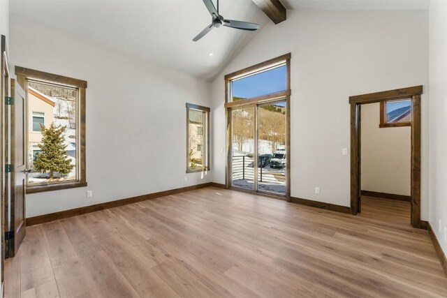 empty room featuring beam ceiling, a wealth of natural light, light hardwood / wood-style flooring, and ceiling fan