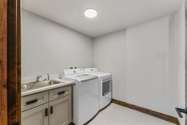 laundry room featuring washer and dryer, light tile patterned flooring, cabinets, and sink