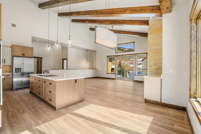 kitchen featuring stainless steel fridge, a kitchen island with sink, high vaulted ceiling, beamed ceiling, and hanging light fixtures