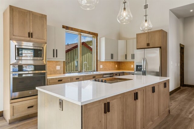 kitchen with white cabinetry, stainless steel appliances, light stone counters, pendant lighting, and a kitchen island