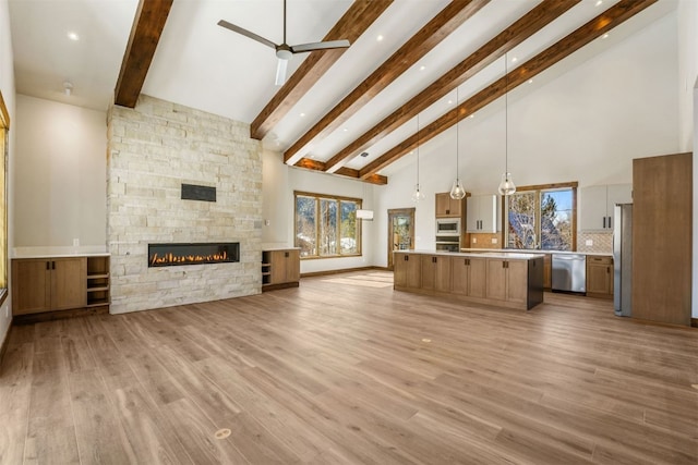 unfurnished living room with a fireplace, light hardwood / wood-style flooring, high vaulted ceiling, and beamed ceiling