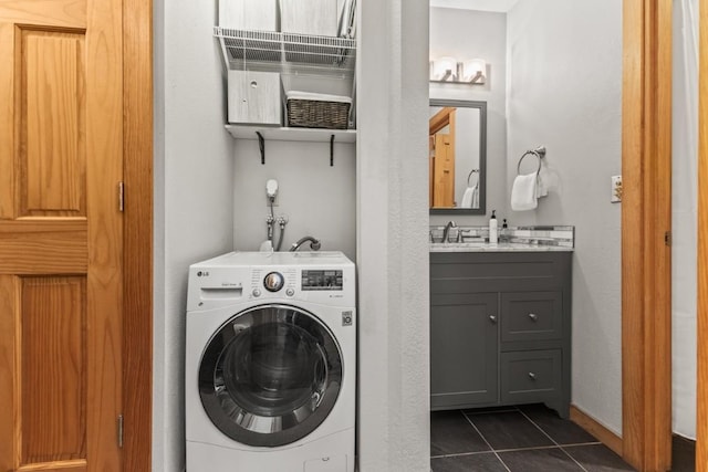 washroom featuring washer / clothes dryer, sink, and dark tile patterned flooring