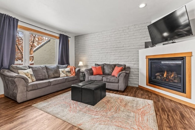 living room featuring brick wall and dark hardwood / wood-style floors