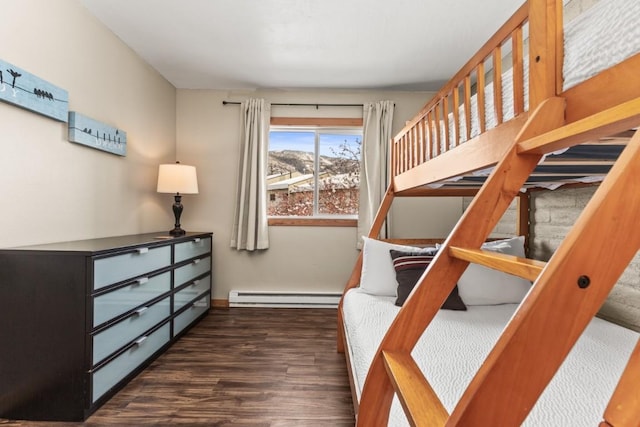 bedroom with dark hardwood / wood-style floors and a baseboard heating unit