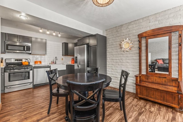 dining space with brick wall, dark hardwood / wood-style flooring, and sink