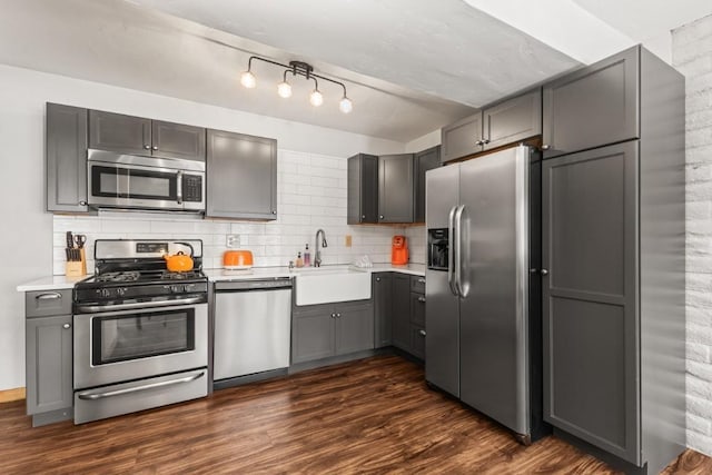 kitchen featuring dark wood-type flooring, sink, gray cabinets, stainless steel appliances, and backsplash