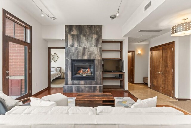 living room with a tiled fireplace and a baseboard heating unit