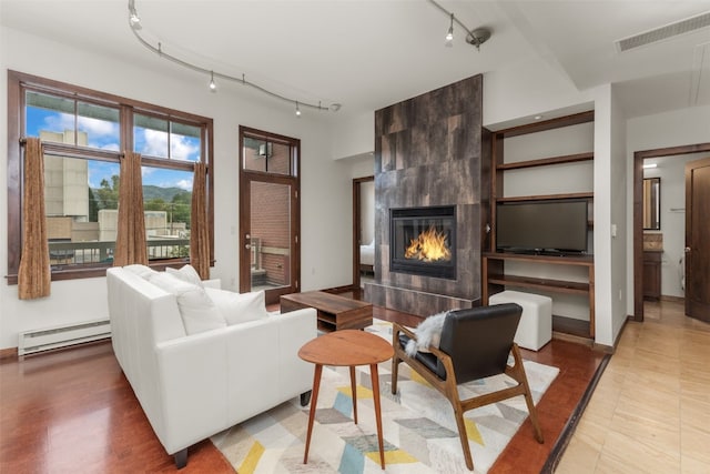 tiled living room featuring a tile fireplace and a baseboard heating unit