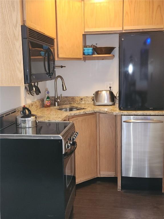 kitchen featuring dark wood-type flooring, light stone counters, sink, and black appliances