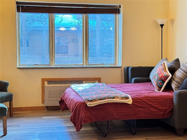 bedroom with hardwood / wood-style flooring and radiator heating unit