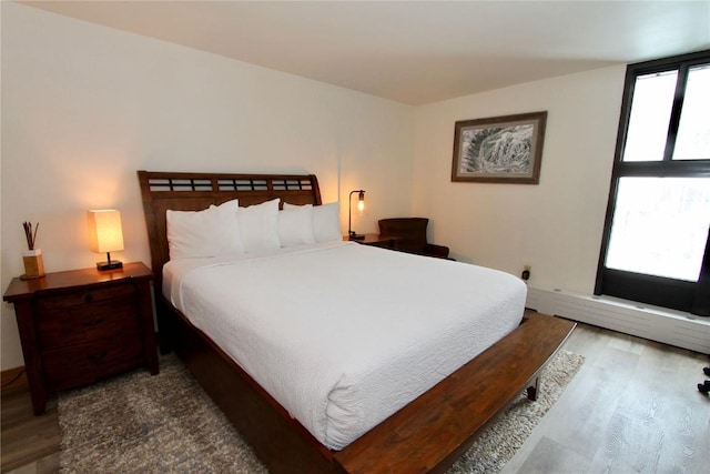 bedroom featuring baseboard heating and hardwood / wood-style floors