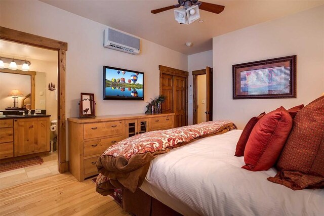 bedroom with a wall mounted AC, ceiling fan, and light hardwood / wood-style floors