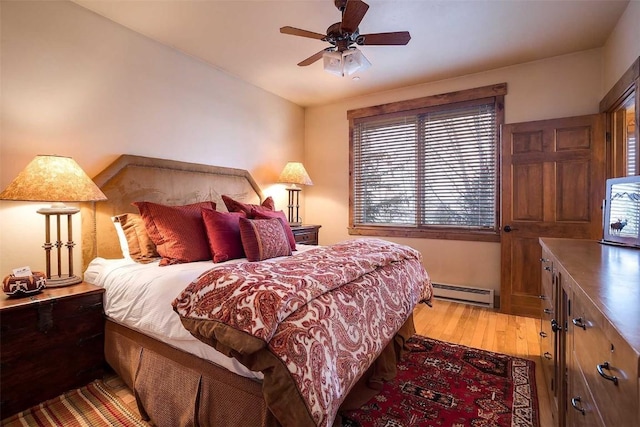 bedroom with light hardwood / wood-style flooring, ceiling fan, and a baseboard heating unit