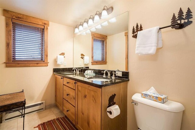 bathroom with a wealth of natural light, vanity, baseboard heating, tile patterned flooring, and toilet