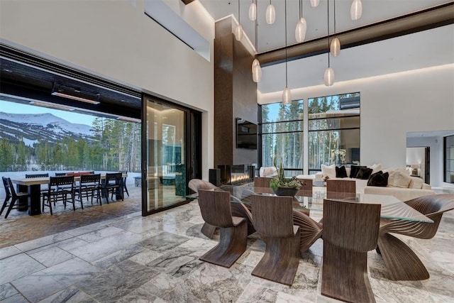 dining area featuring a mountain view, a fireplace, and a towering ceiling