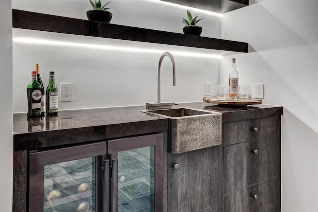 bar featuring dark brown cabinetry, sink, and wine cooler