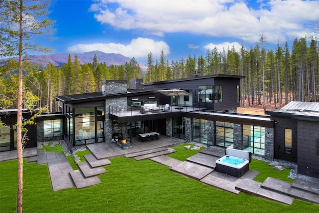 rear view of house featuring a lawn, a mountain view, and a patio area