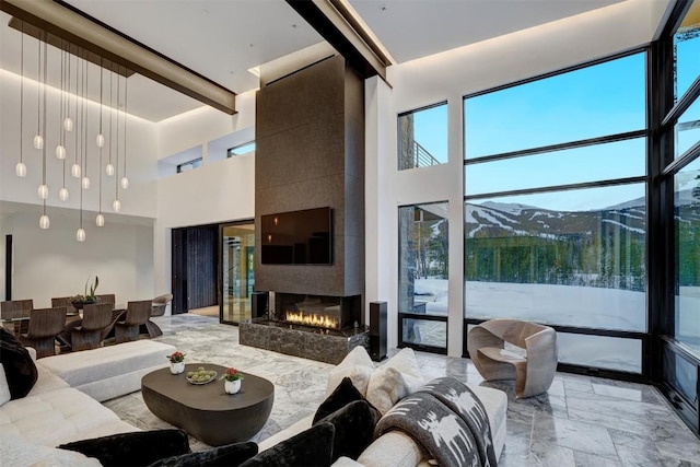 living room with beamed ceiling, a towering ceiling, and a tiled fireplace