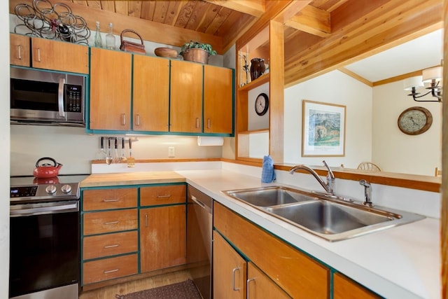 kitchen with light countertops, appliances with stainless steel finishes, brown cabinetry, and a sink