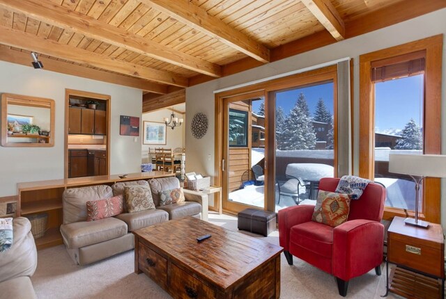 living area with wooden ceiling, light carpet, a notable chandelier, and beamed ceiling