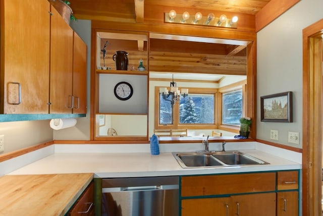 kitchen featuring brown cabinetry, an inviting chandelier, light countertops, stainless steel dishwasher, and a sink