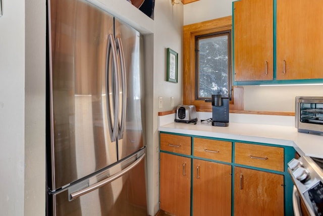 kitchen with light countertops, range, freestanding refrigerator, and a toaster