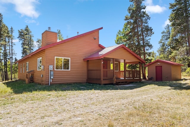 back of property with a storage shed and a lawn