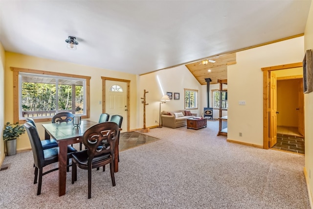 dining space featuring carpet, a wood stove, plenty of natural light, and lofted ceiling