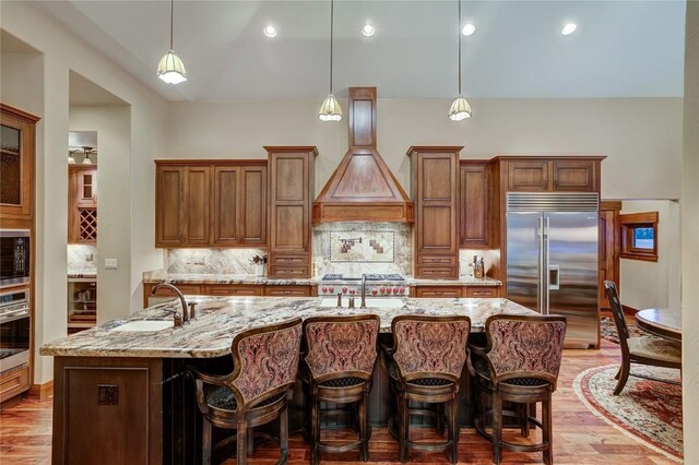 kitchen featuring pendant lighting, a spacious island, built in appliances, and decorative backsplash