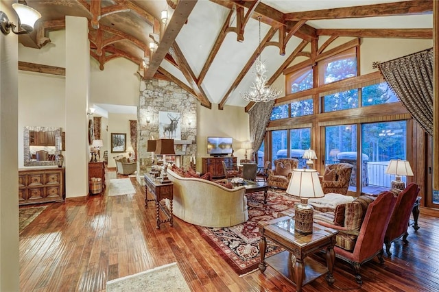 living room featuring hardwood / wood-style flooring, beam ceiling, high vaulted ceiling, a fireplace, and a chandelier