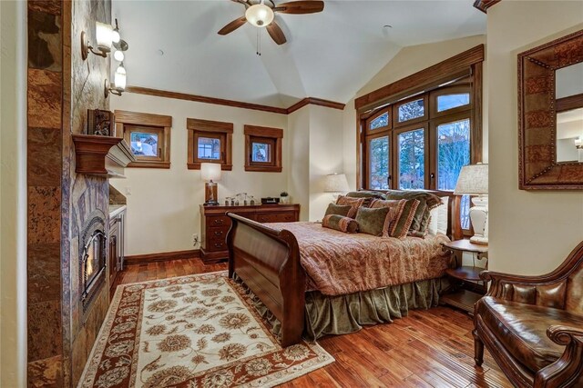 bedroom featuring french doors, lofted ceiling, ceiling fan, a fireplace, and hardwood / wood-style floors