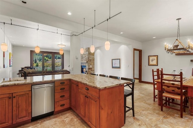 kitchen with a breakfast bar, decorative light fixtures, stainless steel dishwasher, and sink