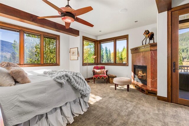 bedroom featuring multiple windows, carpet floors, ceiling fan, and a tiled fireplace