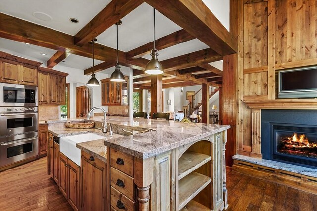 kitchen with hanging light fixtures, sink, light stone countertops, appliances with stainless steel finishes, and a large island