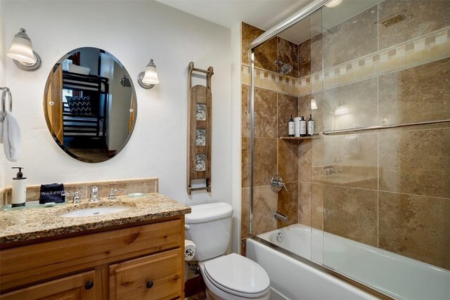 full bathroom with bath / shower combo with glass door, vanity, and toilet