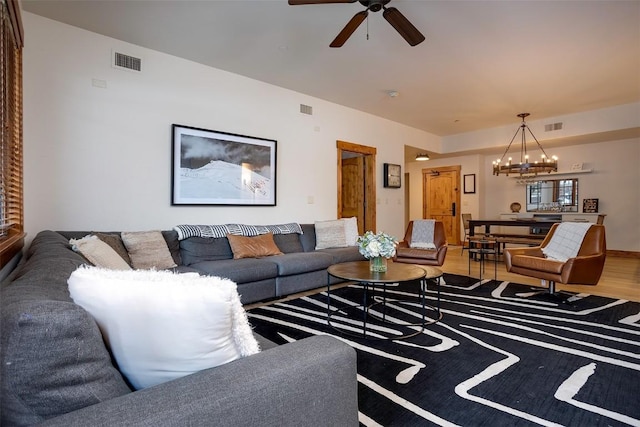 living room with ceiling fan with notable chandelier and wood-type flooring