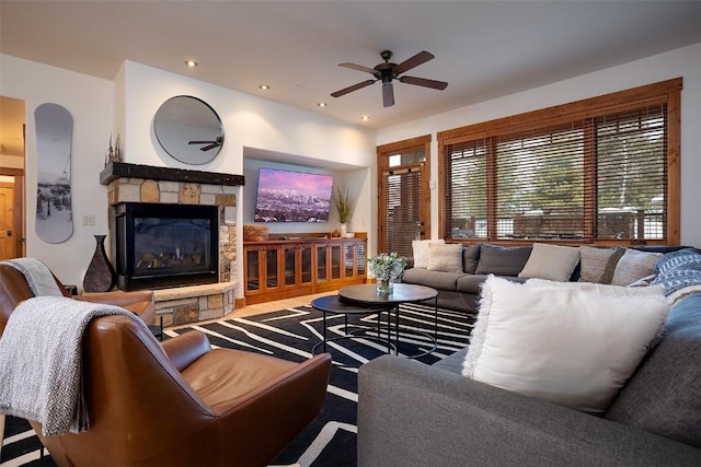 living room with a stone fireplace and ceiling fan