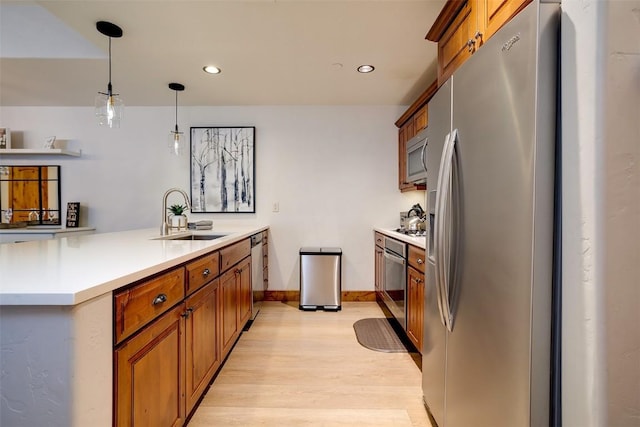 kitchen featuring sink, light wood-type flooring, kitchen peninsula, pendant lighting, and stainless steel appliances