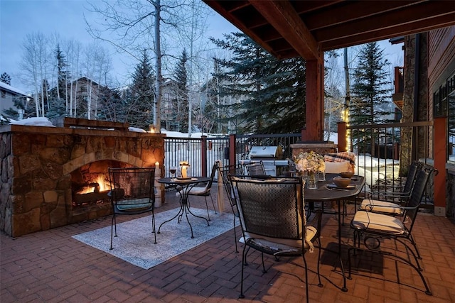 snow covered patio with an outdoor stone fireplace