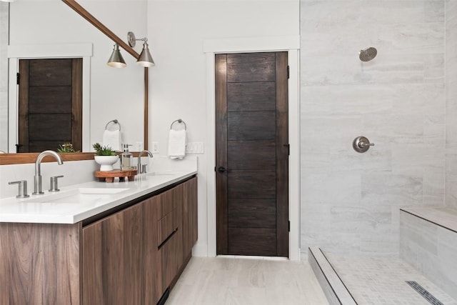 bathroom with a tile shower and vanity