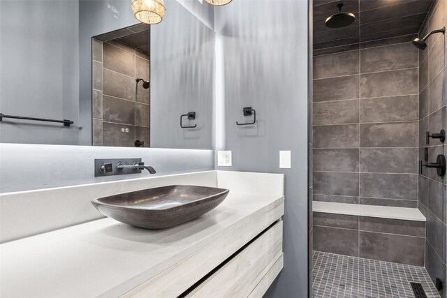 bathroom with a tile shower and vanity