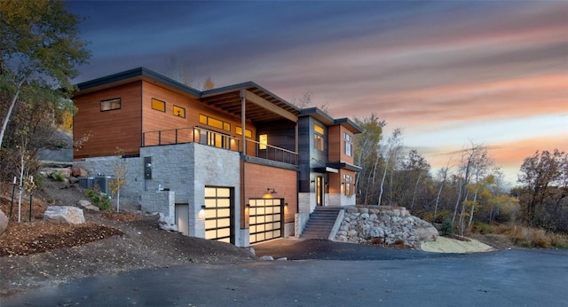 property exterior at dusk with a balcony and a garage