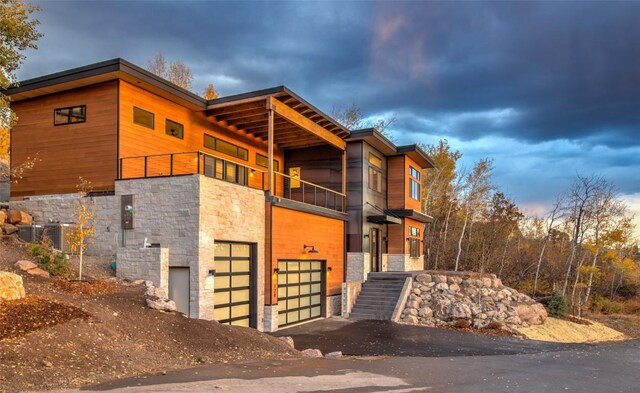 property exterior at dusk with a garage and a balcony