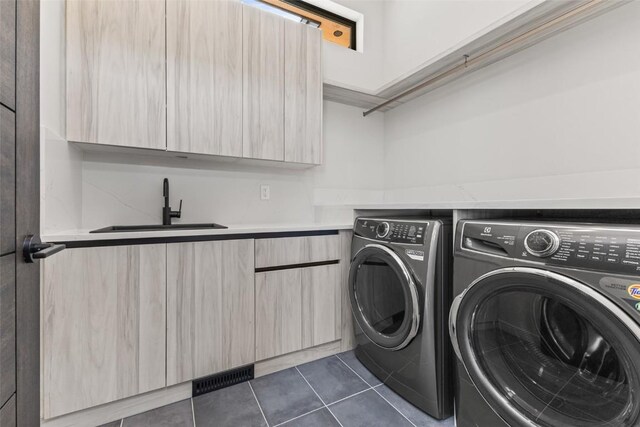 laundry room with cabinets, dark tile patterned floors, sink, and washing machine and clothes dryer