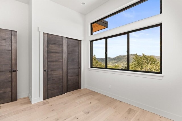 unfurnished bedroom featuring a closet, a mountain view, and light hardwood / wood-style flooring