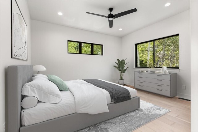 bedroom with multiple windows, light hardwood / wood-style flooring, and ceiling fan